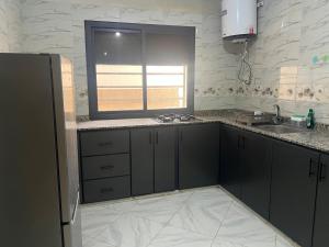 een keuken met zwarte kasten, een gootsteen en een raam bij Luxury University Apartment 3 in Fès +10 foto's