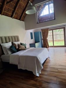 een slaapkamer met een bed en een groot raam bij Harties Safari View in Hartbeespoort