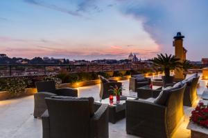 a rooftop patio with chairs and tables with a view of the city at Navona Queen Rooftop in Rome