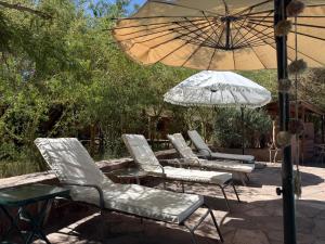 a group of chairs and an umbrella on a patio at Hotel Tulor in San Pedro de Atacama