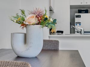 een witte vaas met een boeket bloemen op een tafel bij Serenity One Boutique in Melbourne