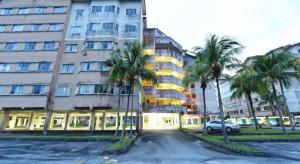a street in front of a large building with palm trees at OYO 90559 Ummul Motel C Mart in Arau