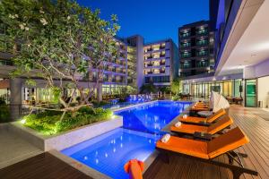 una piscina con tumbonas en un edificio en J Inspired Hotel Pattaya - SHA Extra Plus, en Pattaya central