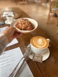 eine Person hält einen Teller mit einer Tasse Kaffee und einem Gebäck in der Unterkunft La Volga Beach Resort in Chopdem + 2 Fotos