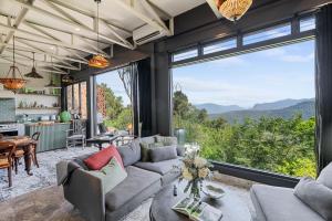 een woonkamer met een bank en een groot raam bij Escape to Serenity in Beechmont Luxurious Cabin Retreat in Beechmont