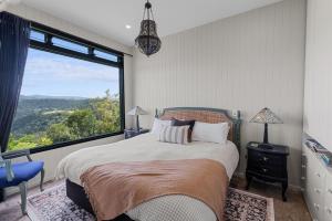 een slaapkamer met een bed met een groot raam bij Escape to Serenity in Beechmont Luxurious Cabin Retreat in Beechmont