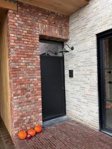a black door in a brick wall with some pumpkins at Tjusteplekske in Heuvelland