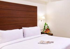 a bedroom with a large white bed with a christmas tree at Deccan Pavilion in Pune