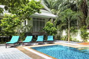 a swimming pool with blue chairs and a house at Baan Aree Villa in Klong Muang Beach