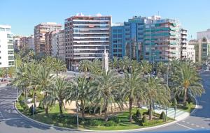 een groep palmbomen in een stad met gebouwen bij Apartamento Luceros in Alicante
