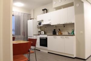 a kitchen with white cabinets and a table and a dining room at Scandinavian Dream Guesthouse and Apartments in Rovaniemi