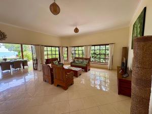 een grote woonkamer met stoelen, tafels en ramen bij Beachfront Villa Mawar with Private Pool and Sunset View in Pengastulan