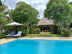 een zwembad met twee stoelen en een parasol en een huis bij Beachfront Villa Mawar with Private Pool and Sunset View in Pengastulan