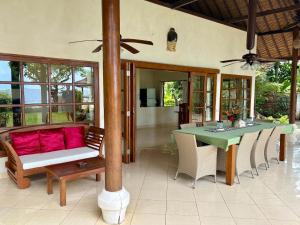 een eetkamer met een tafel en een bank bij Beachfront Villa Mawar with Private Pool and Sunset View in Pengastulan