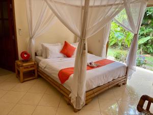een slaapkamer met een hemelbed bij Beachfront Villa Mawar with Private Pool and Sunset View in Pengastulan +66 foto's