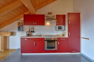 una cucina con armadi rossi e piano cottura di TraumWohnung a Seebruck
