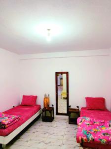 ein Schlafzimmer mit zwei Betten und einem Spiegel in der Unterkunft Dar Jana Tozeur in Tozeur