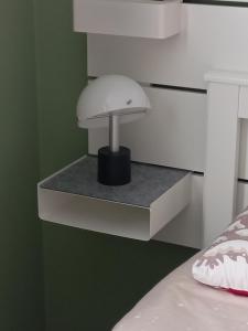 una lampada bianca appoggiata su uno scaffale accanto a un letto di Dimora degli Gnomi a Tirano