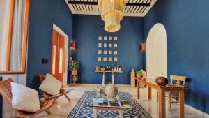 a living room with blue walls and a table and chairs at Casa María Eulalio - Boutique Guesthouse in Mérida
