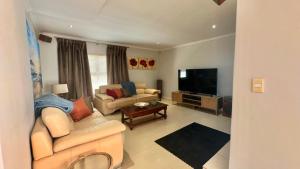 a living room with couches and a flat screen tv at Maison Dauphine in Cape Town