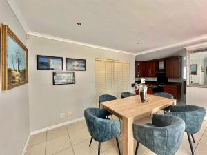 a dining room with a wooden table and blue chairs at Maison Dauphine in Cape Town