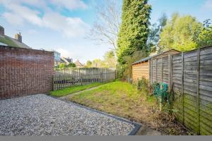 een achtertuin met een hek en een stenen muur bij Keralia in Wivenhoe +15 foto's