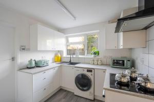 een keuken met witte kasten en een wasmachine bij Keralia in Wivenhoe