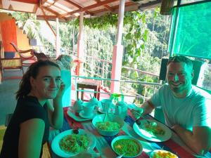 two people sitting at a table with plates of food at Rainforest View in Deniyaya