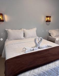 a bed with two swan towels on it at Hospedaria MM in Carolina