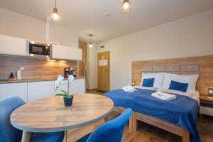 a bedroom with a bed and a table and a kitchen at Apartamenty Pruskie in Karpacz