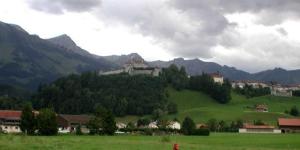 un campo verde con una casa en la cima de una montaña en Hôtel de Ville, en Broc