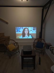 een kamer met twee stoelen en een tv met een vrouw bij Au séchoir à Tabac in Bergerac