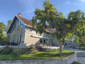 a house with a tree in front of it at Scandinavian Villa with Sea Views Stockholm in Gustavsvik