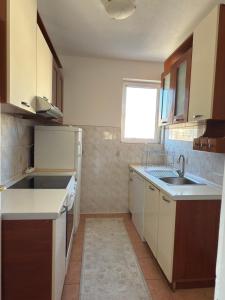 une cuisine avec des armoires blanches, un évier et une fenêtre dans l'établissement Bar Central Stay Apartment, à Bar