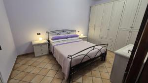 ein Schlafzimmer mit einem Bett mit lila Kissen darauf in der Unterkunft Ninetta in Aielli