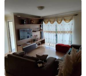 a living room with a couch and a tv at Lindo Por do Sol, Quarto casal com Banheiro privativo, casa compartilhado in Pato Branco