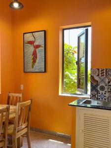 una cucina con pareti arancioni, tavolo e finestra di Orange Villa Muine a Mui Ne