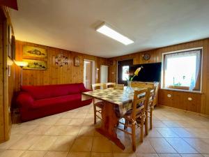 een woonkamer met een tafel en een rode bank bij Maso Patrizia - Rifugio caldo tra le vette in Pieve Tesino