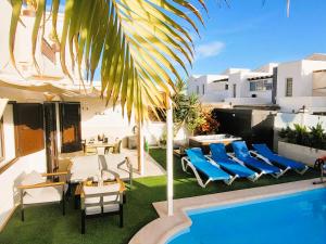 a patio with blue lounge chairs and a swimming pool at Villa Vista with heated pool & Jacuzzi in Playa Blanca