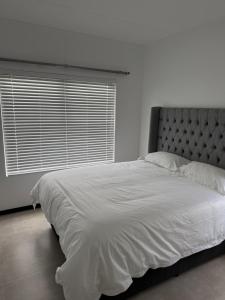 een slaapkamer met een groot wit bed met een raam bij The Grey Luxe Suite in Sandton