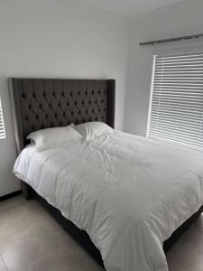 een slaapkamer met een groot wit bed met een hoofdeinde bij The Grey Luxe Suite in Sandton +3 foto's
