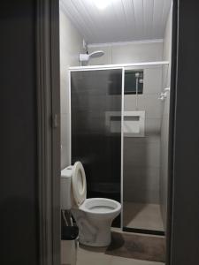 e bagno con servizi igienici e cabina doccia in vetro. di Kitnet e casa mobiliada a Penha