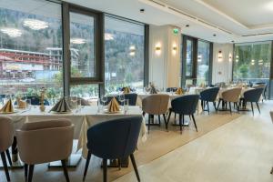 a restaurant with tables and chairs and large windows at Azuga Ski & Bike Resort in Azuga
