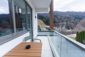 ein Balkon mit einem Holztisch und Glasfenstern in der Unterkunft Azuga Ski and Bike Resort in Azuga