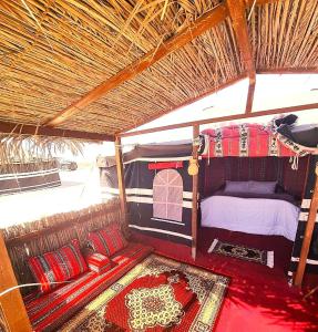 een kamer met een bed en kussens in een tent bij Beach Moments Camp in Aḑyūḩ