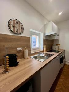 een keuken met een wastafel en een klok aan de muur bij T4 L'essentiel Gare d'Oullins - 3 chambres - 4 lits - 15 min de Lyon in Oullins