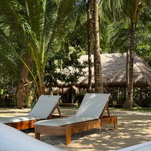 due sedie a sdraio su una spiaggia con palme di Cambaya Beach Resort a Busuanga