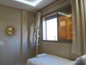 Schlafzimmer mit einem Bett, einem Fenster und einem Spiegel in der Unterkunft Shams house in Imsouane