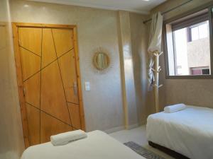 1 Schlafzimmer mit 2 Betten, einer Tür und einem Fenster in der Unterkunft Shams house in Imsouane