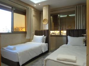 two beds in a room with two windows at Shams House in Imsouane